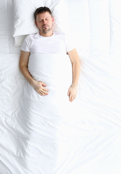 Homme couché sur le dos dans un lit blanc