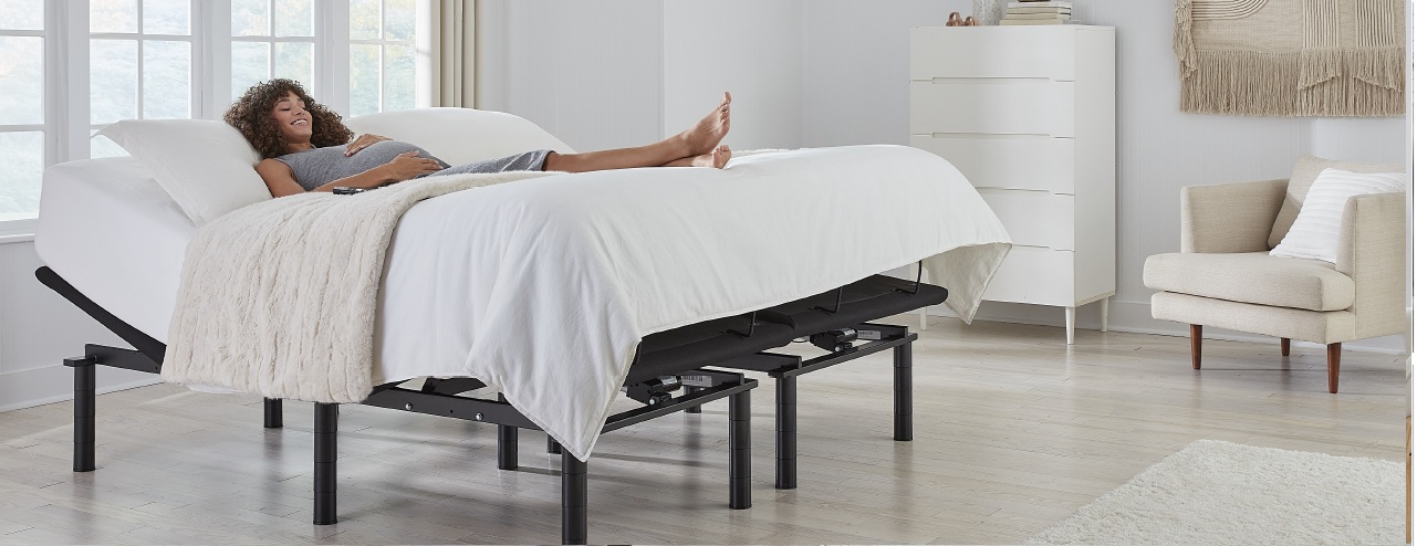 Une femme enceinte sourit, couchée sur une base de lit ajustable.