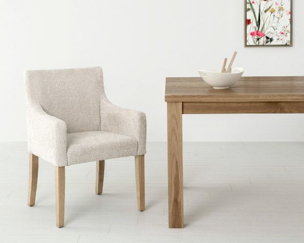Chaise en tissu blanc et table de bois avec un carde derrière.